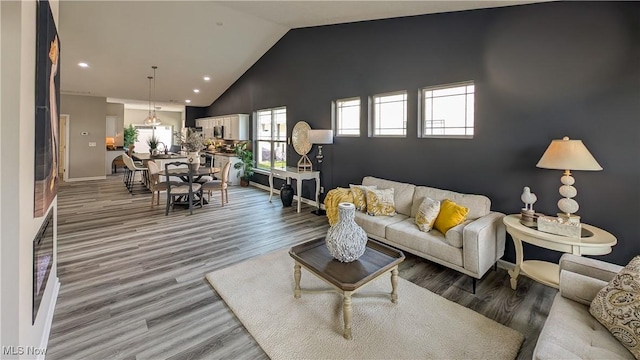living area featuring baseboards, high vaulted ceiling, recessed lighting, and light wood-style flooring
