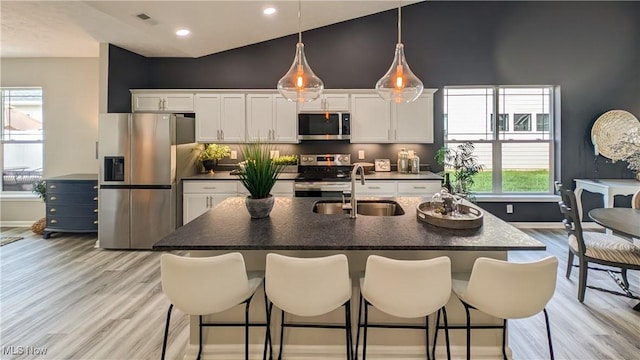 kitchen featuring a sink, a kitchen breakfast bar, dark countertops, and stainless steel appliances