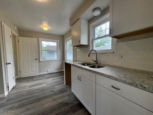 kitchen featuring visible vents, dark wood-type flooring, white cabinets, a sink, and backsplash