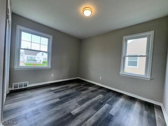 spare room with baseboards, dark wood finished floors, and visible vents