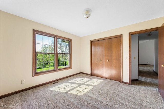 unfurnished bedroom with carpet flooring, baseboards, visible vents, and a closet