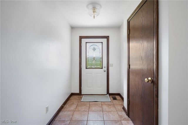 doorway to outside with baseboards, light tile patterned floors, and visible vents