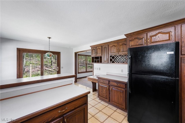 kitchen with freestanding refrigerator, hanging light fixtures, and light countertops