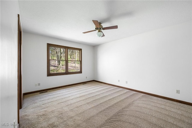 carpeted empty room featuring baseboards, a ceiling fan, and visible vents