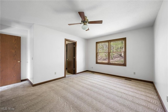 spare room with ceiling fan, baseboards, and carpet