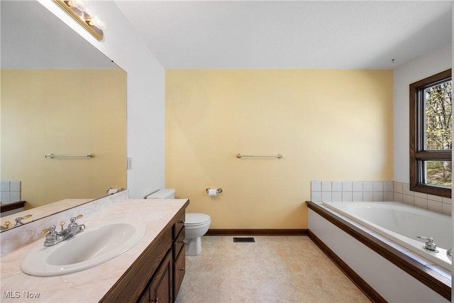bathroom with a garden tub, baseboards, toilet, and vanity