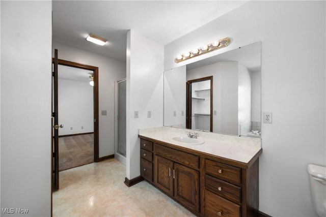 bathroom featuring vanity, baseboards, a shower stall, and toilet
