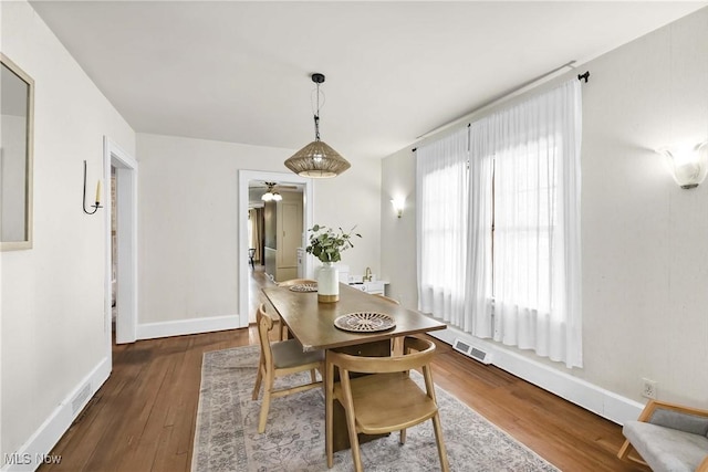 dining space featuring visible vents, a ceiling fan, baseboards, and wood finished floors