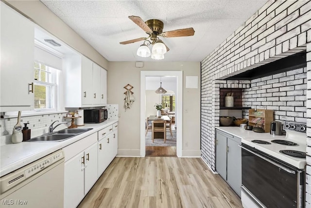 kitchen featuring light countertops, a sink, white appliances, and tasteful backsplash