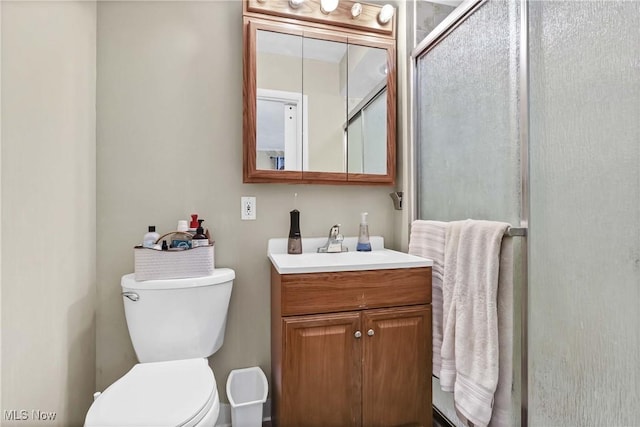 full bathroom with vanity, a shower with door, and toilet