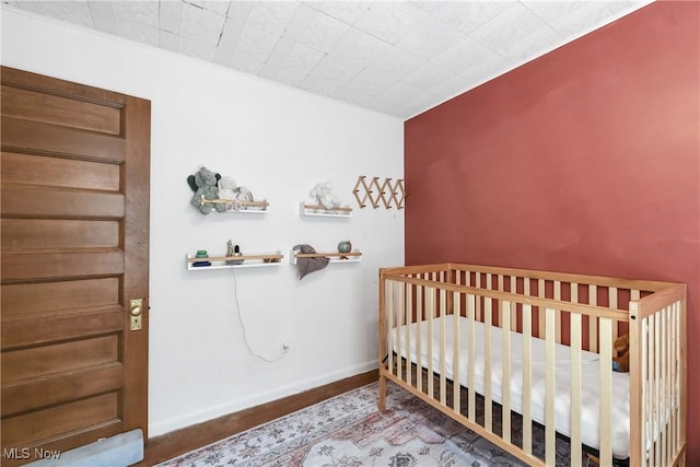 bedroom featuring baseboards and a nursery area