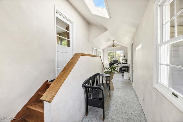 stairway with a ceiling fan and lofted ceiling with skylight