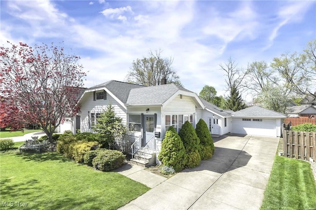 bungalow featuring fence, a front yard, a chimney, an attached garage, and driveway