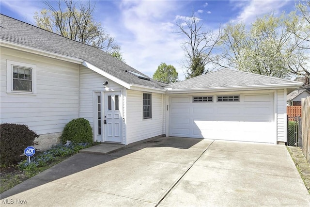 exterior space featuring an attached garage, fence, and a shingled roof