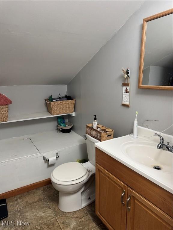 half bath with vanity, toilet, and lofted ceiling