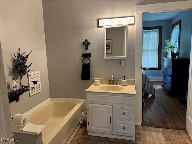 bathroom featuring baseboards, a bath, and vanity