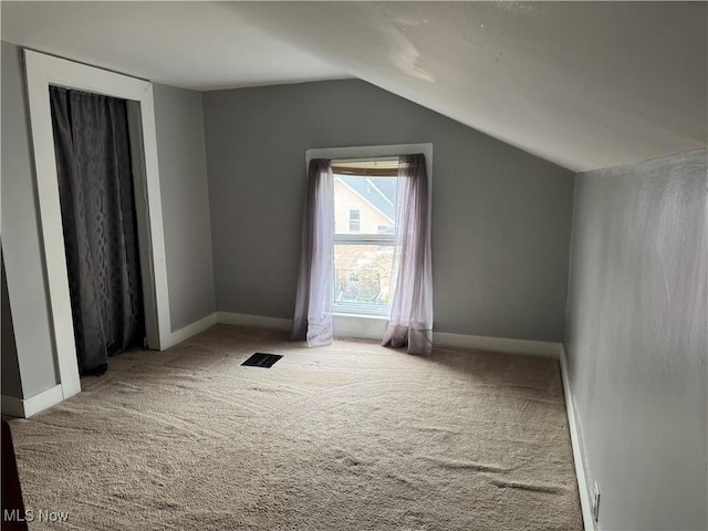 additional living space featuring visible vents, baseboards, carpet, and lofted ceiling