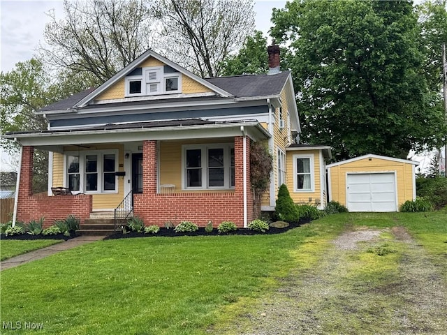 bungalow featuring brick siding, a front yard, an outbuilding, a chimney, and driveway