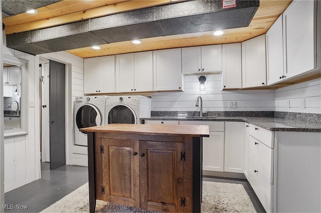 kitchen with washer and dryer, white cabinets, a sink, wood counters, and a kitchen island