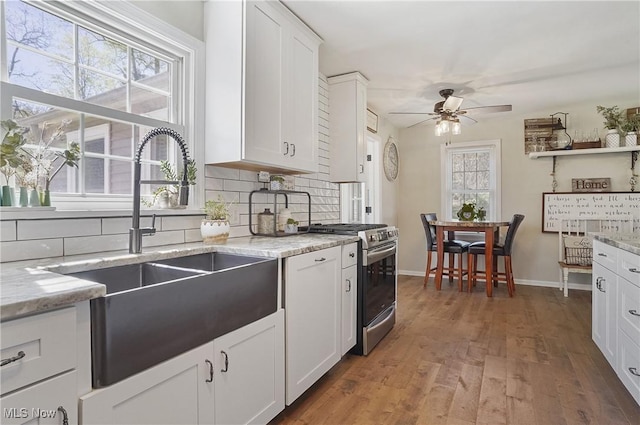 kitchen featuring ceiling fan, tasteful backsplash, wood finished floors, a sink, and stainless steel gas range