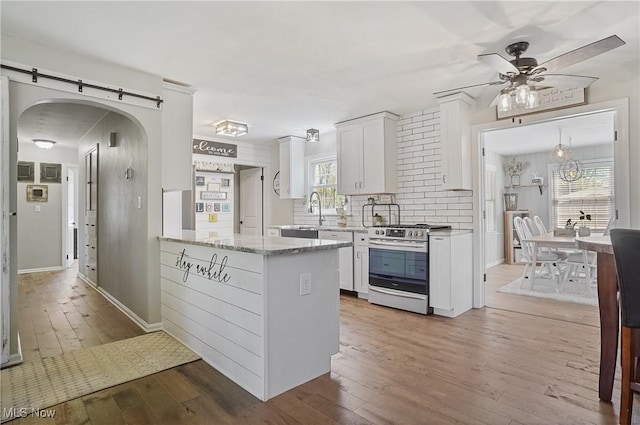 kitchen with wood-type flooring, a sink, white cabinets, stainless steel range with gas stovetop, and a ceiling fan
