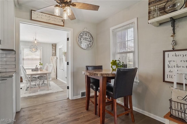 dining space featuring a ceiling fan, baseboards, visible vents, and wood finished floors