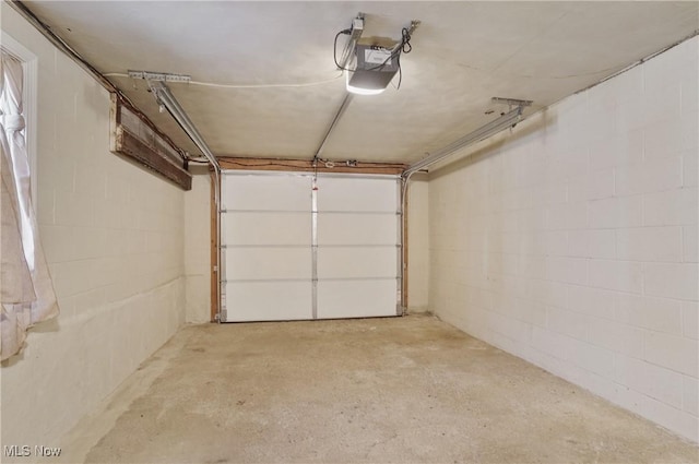 garage featuring concrete block wall and a garage door opener