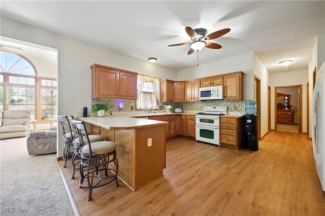 16544 Davis Dr, Calcutta, OH 43920 - kitchen with white appliances, a ceiling fan, a peninsula, a kitchen bar, and backsplash