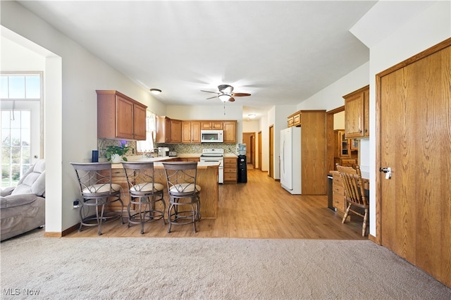 16544 Davis Dr, Calcutta, OH 43920 - kitchen featuring white appliances, a peninsula, ceiling fan, and light carpet