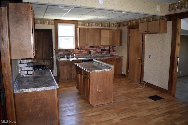 240 S 15th St, Sebring, OH 44672 - kitchen featuring a sink, a drop ceiling, brown cabinets, and light wood-style flooring