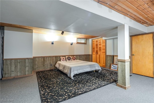 bedroom featuring wainscoting, carpet flooring, and wood walls