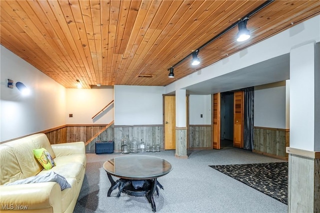 carpeted living room with rail lighting, wood walls, a wainscoted wall, stairs, and wood ceiling