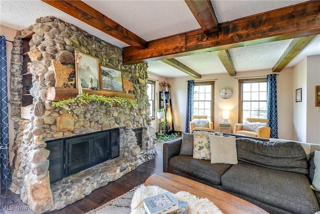 living area featuring beam ceiling, a textured ceiling, wood finished floors, and a fireplace