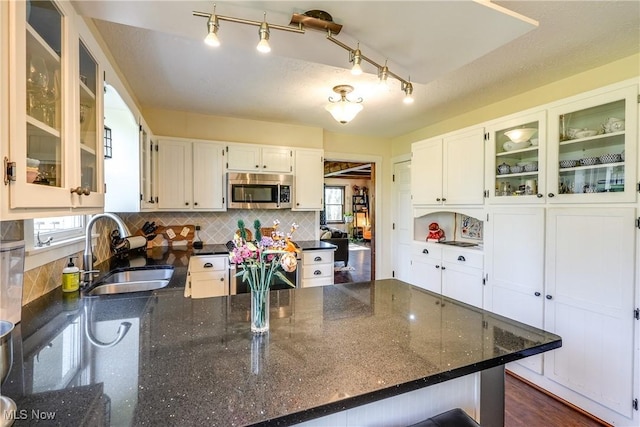 kitchen with decorative backsplash, stainless steel microwave, a wealth of natural light, and a sink