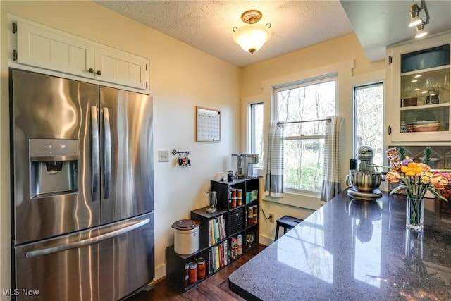 kitchen featuring white cabinets, dark wood-style flooring, stainless steel fridge, baseboards, and stone counters