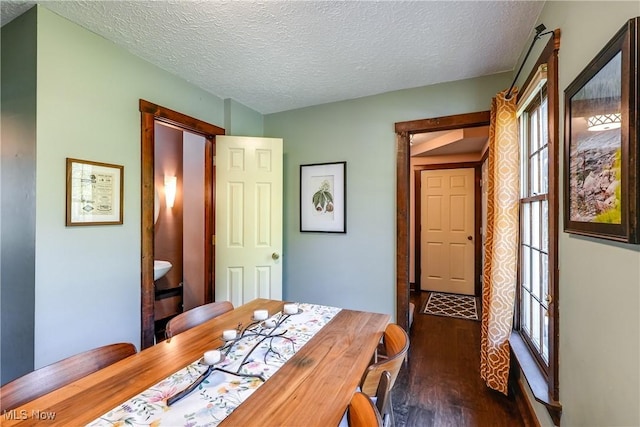 dining room featuring a healthy amount of sunlight, dark wood-style flooring, and a textured ceiling