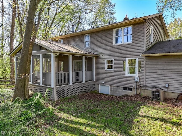 back of property featuring central AC unit, metal roof, a sunroom, and a chimney