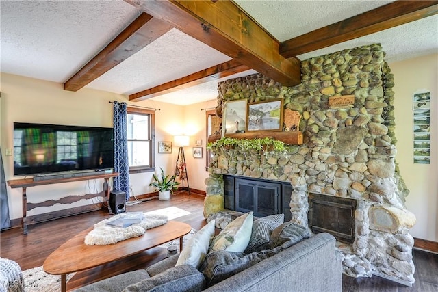 living room featuring a textured ceiling, a stone fireplace, and wood finished floors