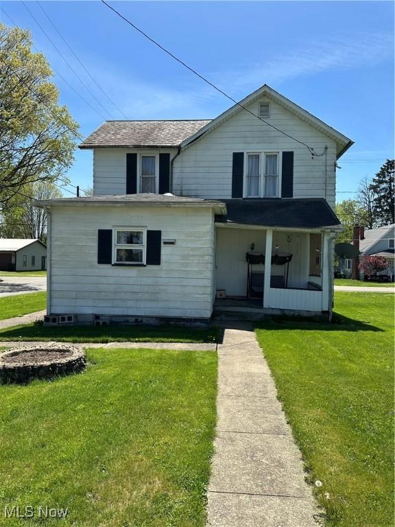 traditional home featuring covered porch and a front yard