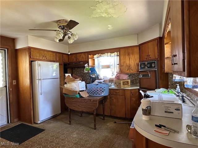 kitchen featuring light countertops, ceiling fan, freestanding refrigerator, and brown cabinets
