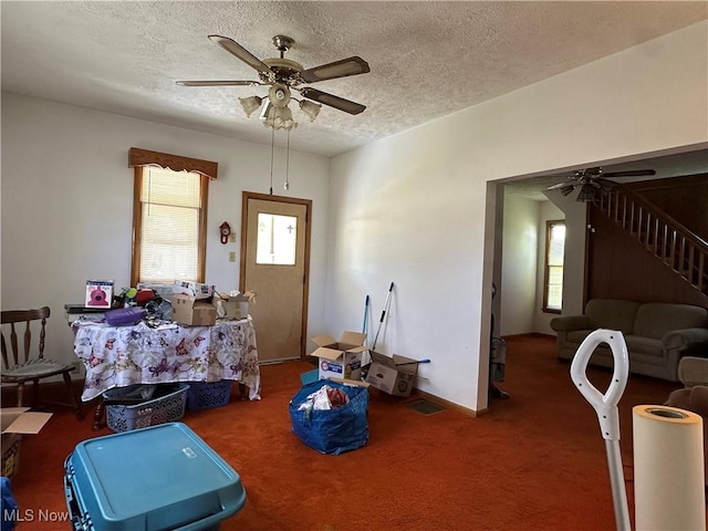 interior space with a ceiling fan, a textured ceiling, baseboards, and stairway