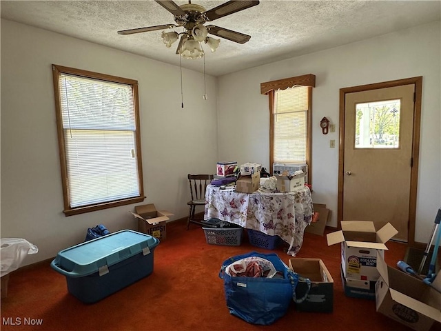 carpeted bedroom featuring a ceiling fan and a textured ceiling