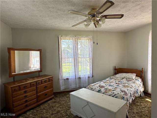 bedroom with dark carpet, a textured ceiling, and ceiling fan