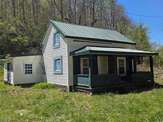 view of side of property featuring a yard, a porch, and metal roof