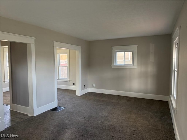 empty room with dark colored carpet, baseboards, and visible vents