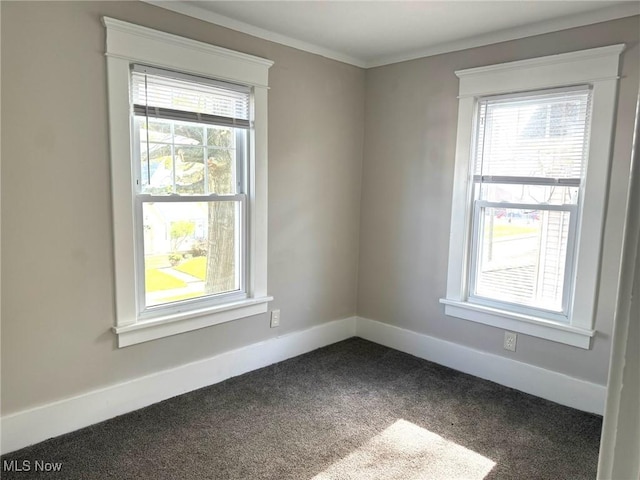 unfurnished room featuring baseboards, ornamental molding, a wealth of natural light, and dark colored carpet