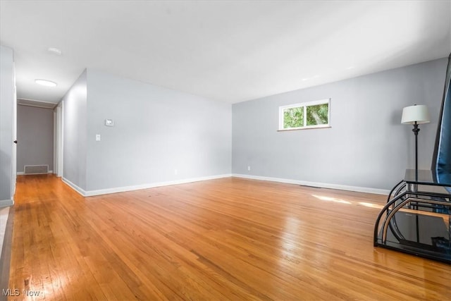 unfurnished living room featuring visible vents, light wood finished floors, and baseboards