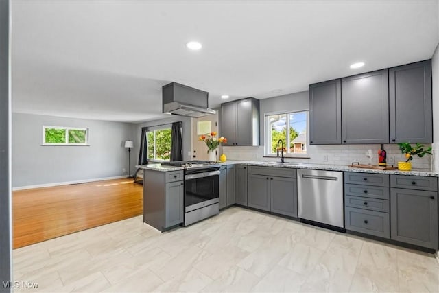 kitchen with decorative backsplash, gray cabinets, exhaust hood, a peninsula, and stainless steel appliances