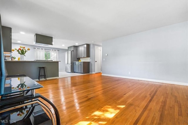 living area featuring baseboards, recessed lighting, and light wood-style flooring