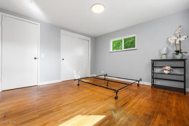 unfurnished bedroom featuring wood-type flooring, baseboards, and a baseboard heating unit
